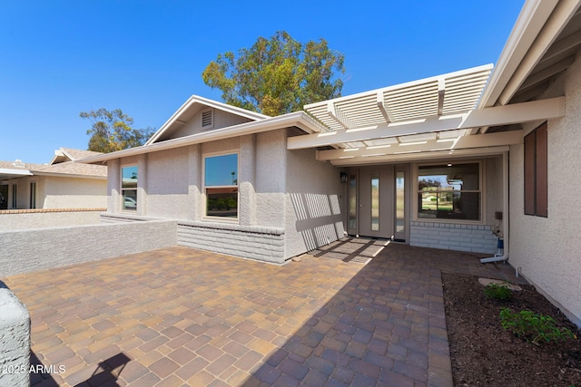 doorway to property with a patio area, a pergola, and stucco siding