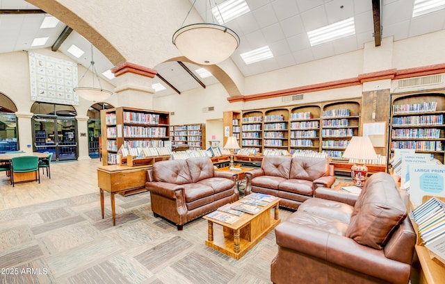 living area with bookshelves, beamed ceiling, arched walkways, high vaulted ceiling, and ornate columns