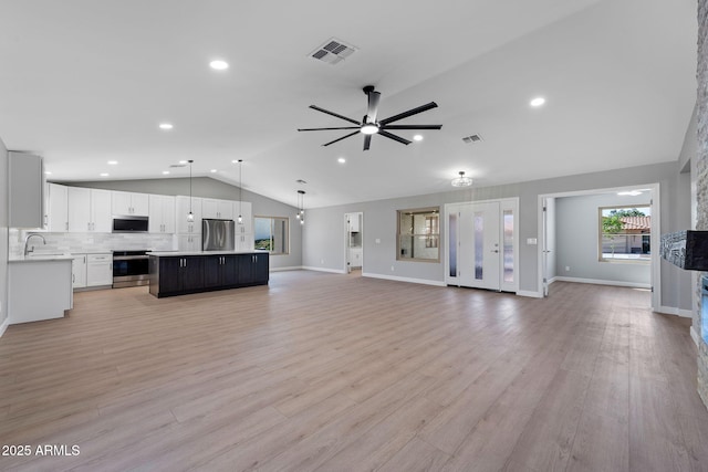 unfurnished living room featuring a sink, visible vents, lofted ceiling, and light wood-style floors