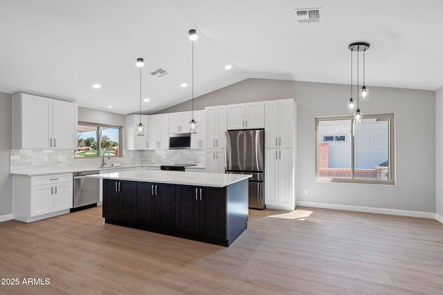 kitchen featuring visible vents, a sink, a kitchen island, stainless steel appliances, and light countertops