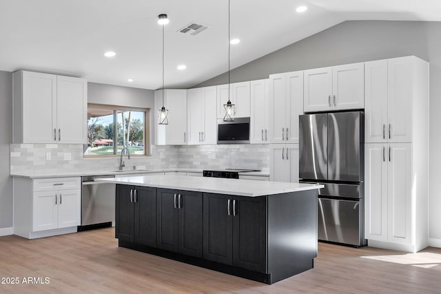 kitchen with visible vents, a kitchen island, stainless steel appliances, white cabinetry, and a sink