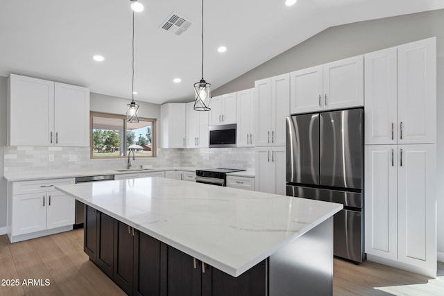 kitchen with visible vents, electric stove, a sink, white cabinetry, and freestanding refrigerator