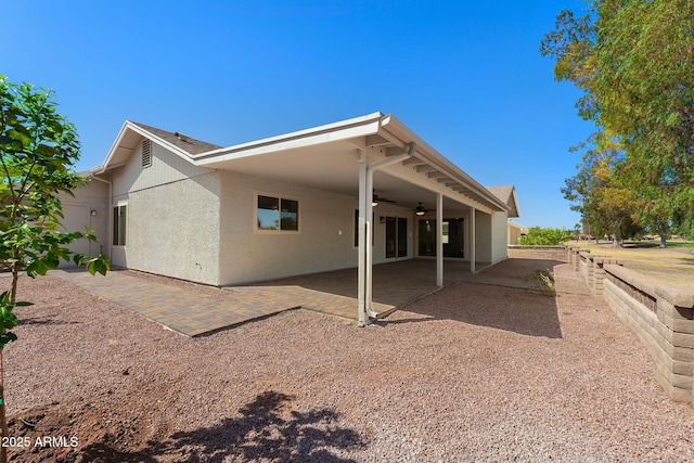 rear view of property featuring a ceiling fan, a patio area, fence, and stucco siding