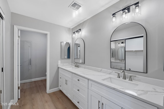 bathroom with double vanity, visible vents, wood finished floors, and a sink