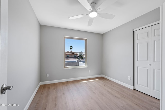 unfurnished bedroom with light wood-type flooring, baseboards, a closet, and ceiling fan