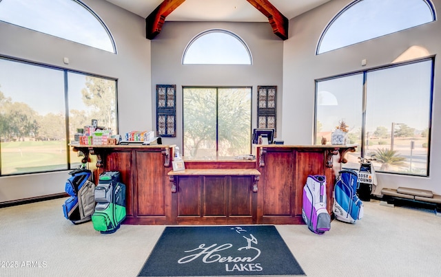 miscellaneous room with beam ceiling, a high ceiling, and carpet flooring