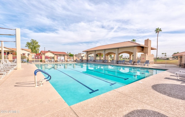 community pool with a patio and fence