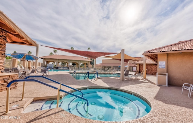 community pool with a patio and a hot tub