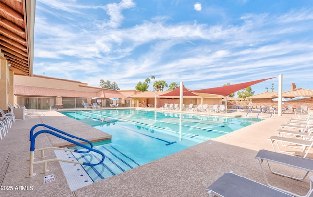 community pool with a patio area and fence