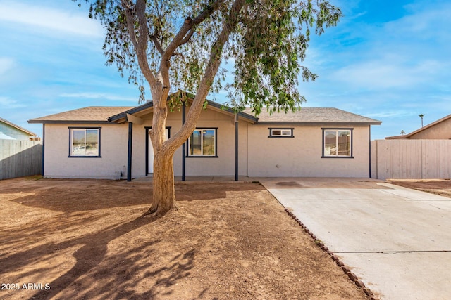 rear view of house with stucco siding, fence, and a patio