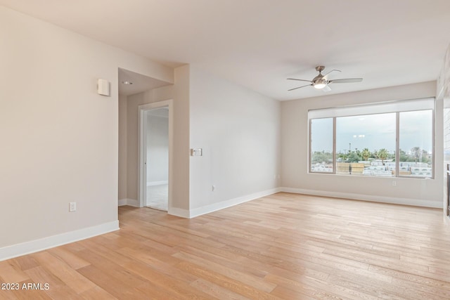spare room with ceiling fan, light wood-style flooring, and baseboards