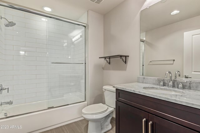 bathroom with toilet, shower / bath combination with glass door, wood finished floors, vanity, and recessed lighting