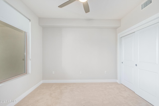 unfurnished bedroom featuring light colored carpet, ceiling fan, and a closet