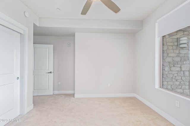 spare room featuring light carpet, ceiling fan, a smoke detector, and baseboards