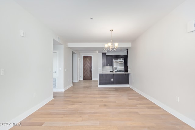 unfurnished dining area featuring sink, an inviting chandelier, and light hardwood / wood-style floors