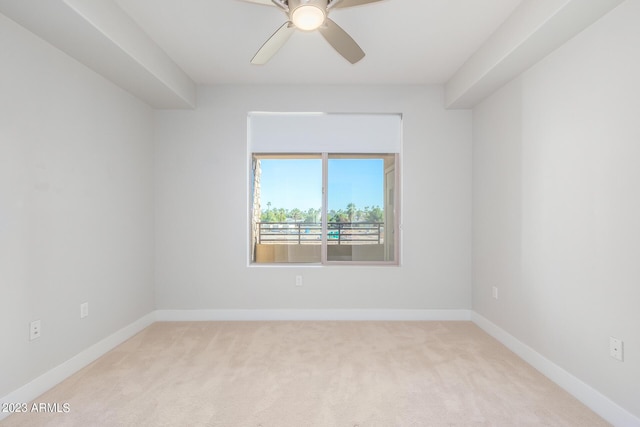 spare room featuring light carpet, a ceiling fan, and baseboards