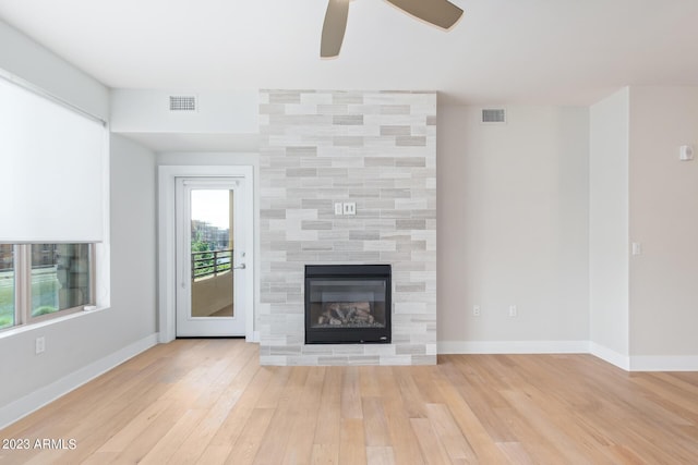 unfurnished living room featuring wood finished floors, ceiling fan, a fireplace, and baseboards