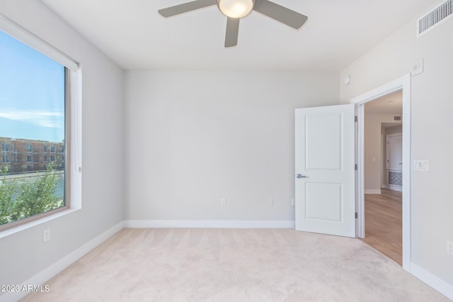 unfurnished room featuring a ceiling fan, light colored carpet, and baseboards