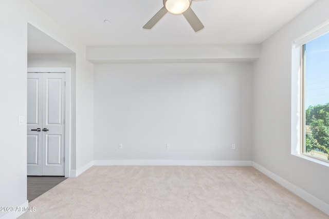 carpeted spare room with ceiling fan and baseboards