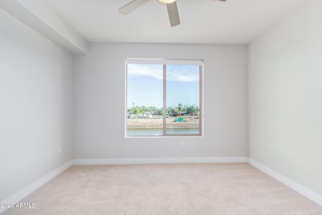 spare room with light colored carpet, ceiling fan, and baseboards