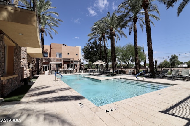 community pool featuring a patio, fence, and a hot tub