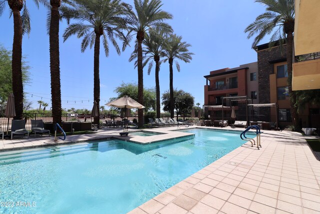 view of swimming pool featuring a hot tub and a patio