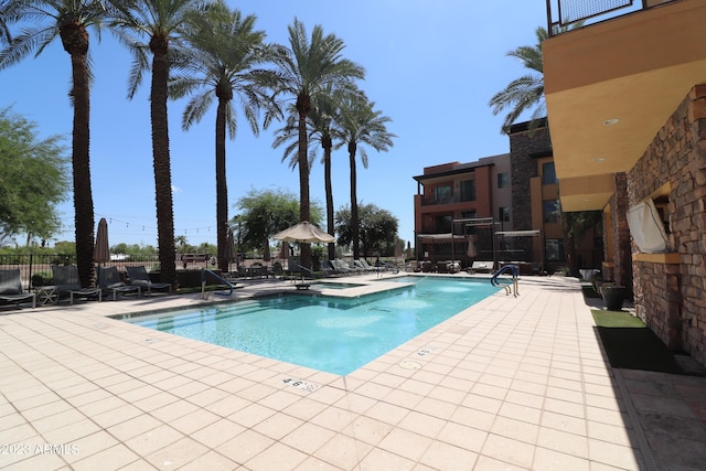 view of swimming pool with a patio, fence, and a pool with connected hot tub