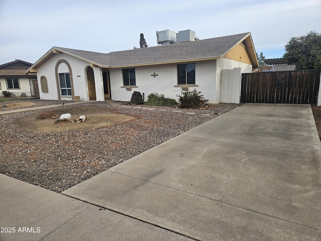 ranch-style house featuring stucco siding, concrete driveway, fence, and a gate