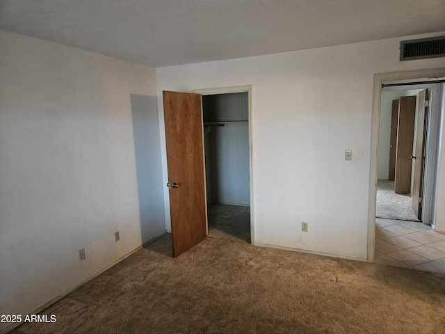 unfurnished bedroom with visible vents, carpet, a closet, and a walk in closet