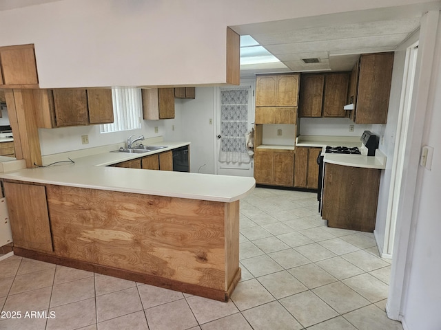 kitchen featuring dishwasher, a peninsula, light tile patterned flooring, and light countertops