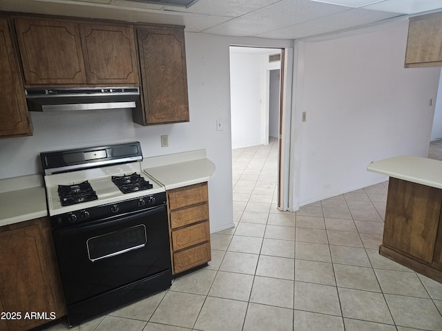 kitchen with light tile patterned floors, gas stove, light countertops, and extractor fan