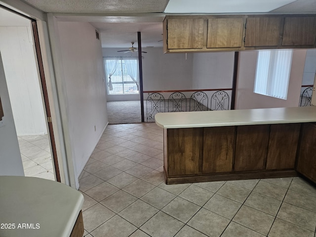 kitchen featuring visible vents, a peninsula, light tile patterned flooring, ceiling fan, and light countertops