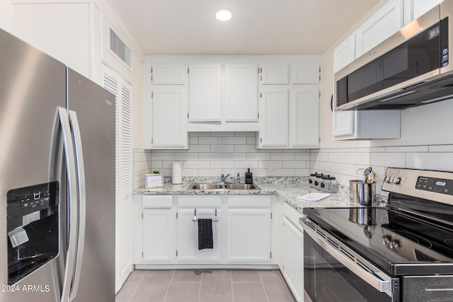 kitchen featuring light stone counters, sink, white cabinetry, appliances with stainless steel finishes, and decorative backsplash