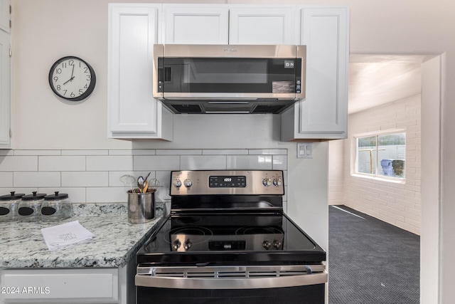 kitchen featuring decorative backsplash, light stone counters, stainless steel appliances, and white cabinets