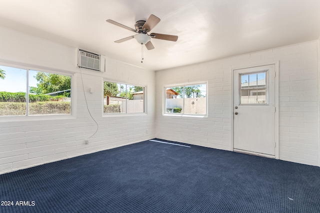 carpeted empty room with ceiling fan, a wall mounted air conditioner, and brick wall