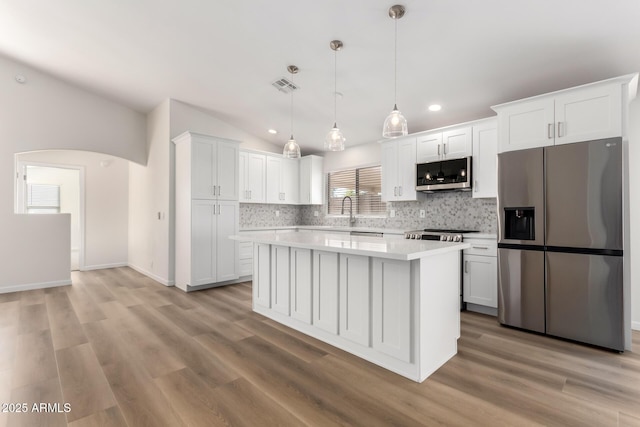 kitchen with lofted ceiling, appliances with stainless steel finishes, and white cabinetry