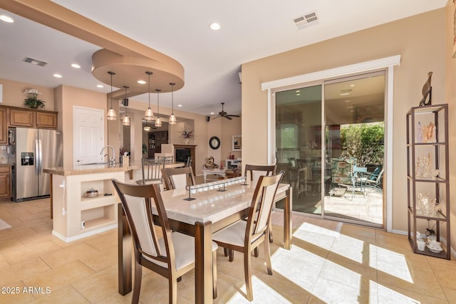 tiled dining room with ceiling fan and sink