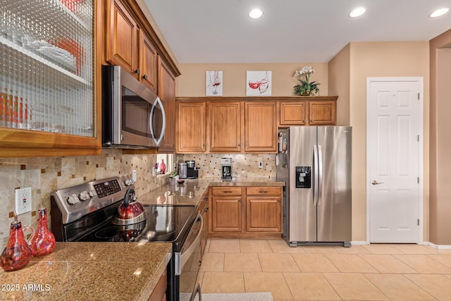 kitchen featuring light tile patterned floors, decorative backsplash, appliances with stainless steel finishes, and light stone counters