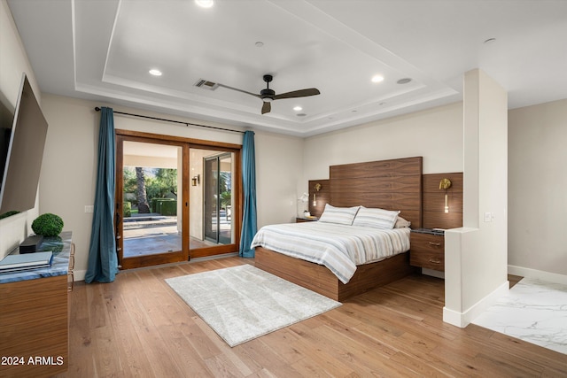 bedroom featuring a raised ceiling, ceiling fan, access to exterior, and light wood-type flooring