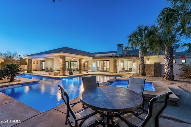 pool at dusk with an in ground hot tub and a patio area