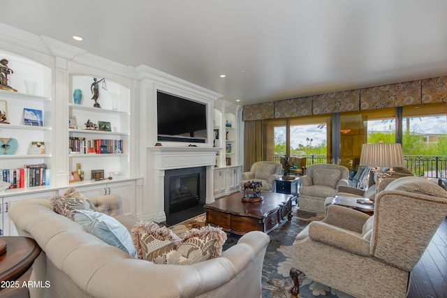 living area featuring built in features, a glass covered fireplace, and recessed lighting