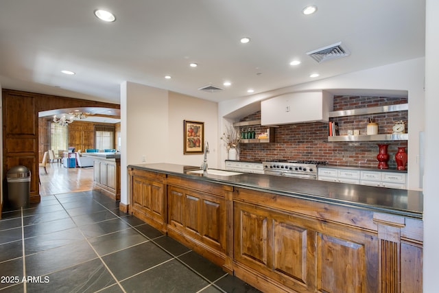 kitchen with visible vents, range with two ovens, arched walkways, a sink, and dark countertops