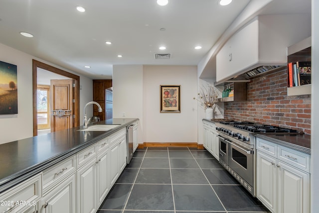 kitchen with dark countertops, decorative backsplash, recessed lighting, stainless steel appliances, and a sink