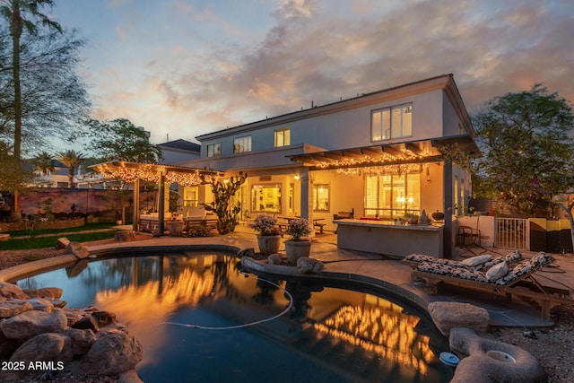 1421 W Saltsage Dr, Phoenix, AZ 85045 - back of house at dusk with stucco siding, a patio area, fence, and an outdoor hangout area