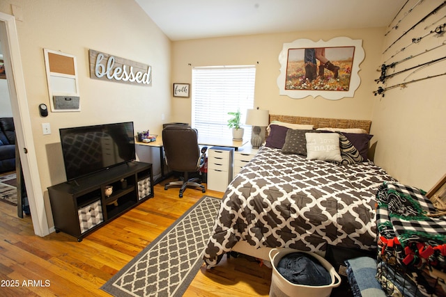 bedroom with vaulted ceiling and light wood-type flooring