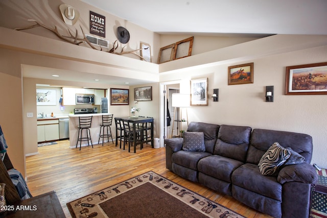 living room with vaulted ceiling and light hardwood / wood-style flooring