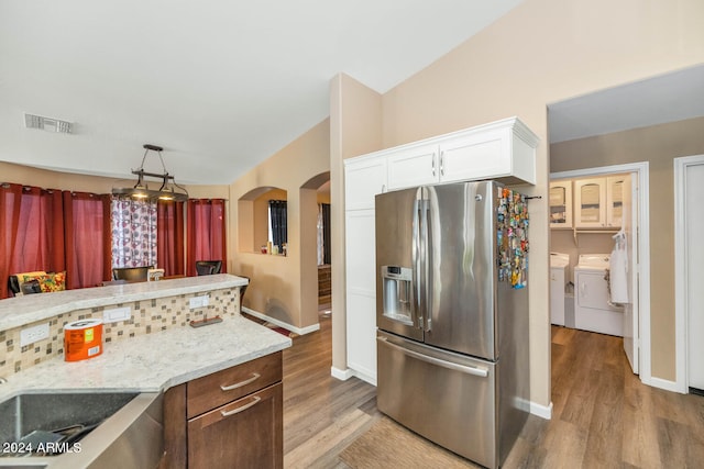 kitchen featuring stainless steel fridge, independent washer and dryer, white cabinetry, and light hardwood / wood-style flooring