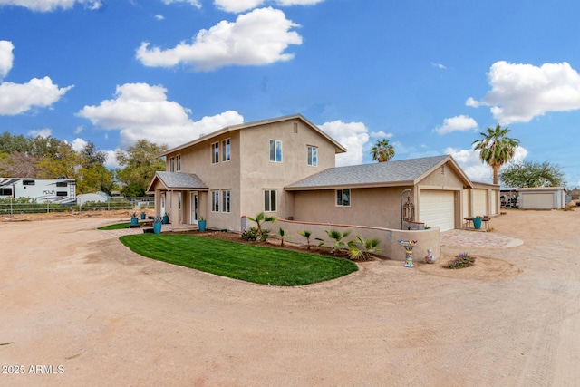 view of front of property with a front yard, fence, dirt driveway, and stucco siding