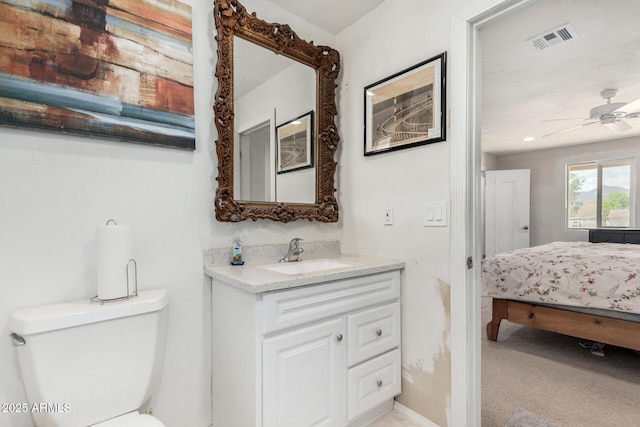 bathroom featuring connected bathroom, toilet, vanity, visible vents, and a ceiling fan