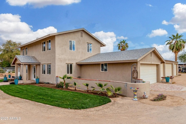 traditional-style home featuring a garage, a front yard, roof with shingles, and stucco siding